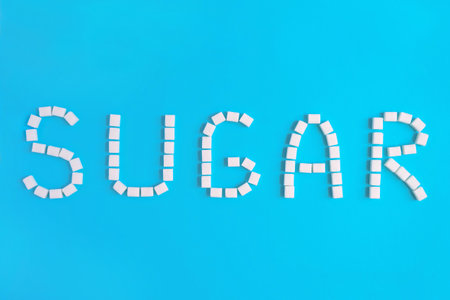 pieces of sugar laid out in the inscription SUGAR on blue backgroundの写真素材