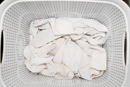 Dirty clothes and mens white shirts in the laundry basketの写真素材