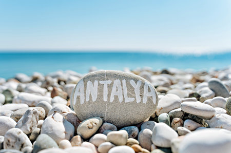 stones on the beach with a blue sea and the inscription antalyaの写真素材