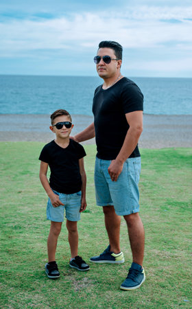 Handsome father and cute son staying together with identical clothesの写真素材