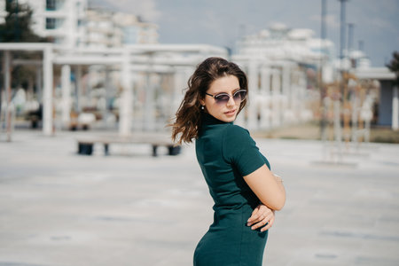 A beautiful young brunette girl is walking in the city in sunglasses and posing for the camera. Sunny weather and promenade in Antalyaの写真素材