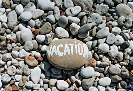 stones on the beach with a blue sea and the inscription vacationの写真素材