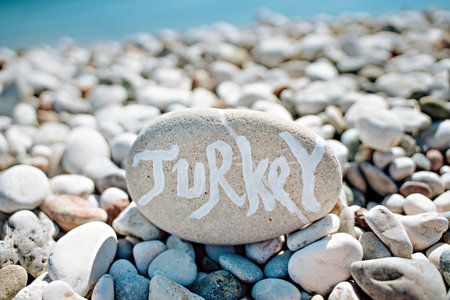 stones on the beach with a blue sea and the inscription turkeyの写真素材