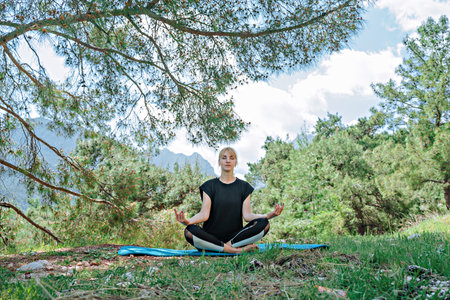 Woman doing yoga poses outside and beautiful view of mountains and forestの写真素材
