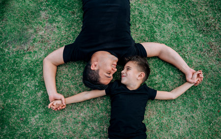 Father and son looking at each other holding handsの写真素材