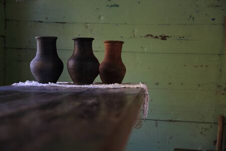 Krynka. Three old pots of clay for milk stand on a wooden table in an old Russian hut against the wall.の写真素材
