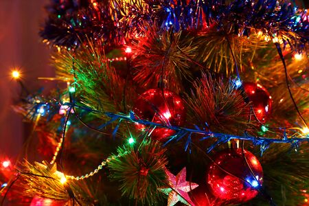 Decorated for the holiday Christmas tree with a lighted garland, tinsel and Christmas toys.の写真素材