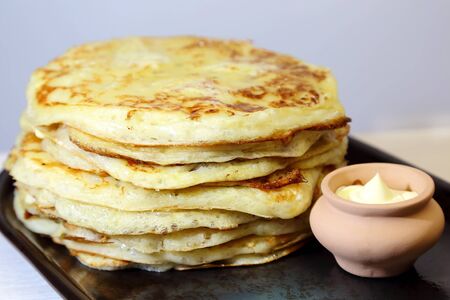 Food. Appetizing baked thick yeast pancakes are stacked on a plate on the table.