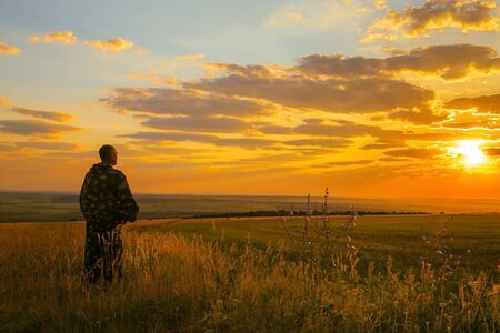 Human and nature. A European man stands in a field, looking into the distance to the horizon and...