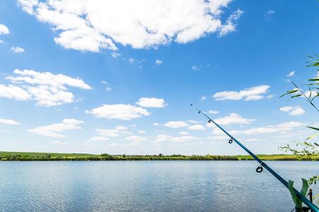 Summer landscape with a beautiful blue lake and green fields against a blue sky. Hiking, fishing on...