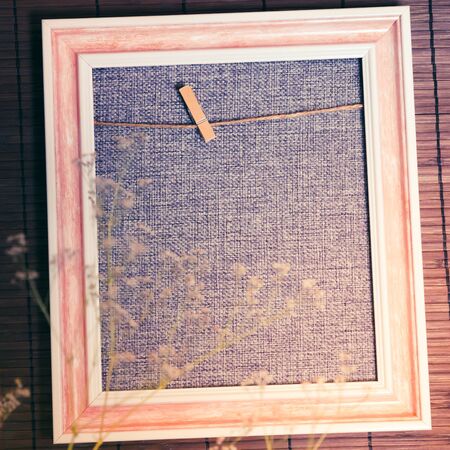Original photo frame blank in gray, pink and beige colors for home decor with natural dry flowers with a rough texture with a copy spaceの写真素材