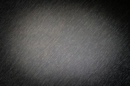 Abstract horizontal diagonal gloomy dark gray black vignetted empty rough monochrome background with textile fabric surface texture in horror style, copy space for text, spot of light in the centerの写真素材
