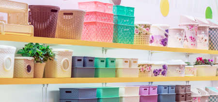 A lot of plastic household goods for home and everyday life, colorful products on the shelf of a store window, containers, buckets, storage baskets, basinsの写真素材