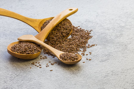 Flax seeds in a wooden spoon on a concrete background, a dietary product that reduces cholesterol, a source of omega-3, vitamins B and C, trace elements, iodine, phosphorus, potassium, magnesium, nickelの写真素材