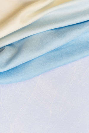 Textile background with the texture of a knitted scarf stole, blue creamy yellow fabric with a color gradient in pastel shades with copy space, clothes and accessories.の写真素材