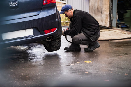 Saratov, Russia - 01/11/2020: Tire fitting, car service, profession, male mechanic serviceman is replacing a summer wheel with a winter one.のeditorial素材