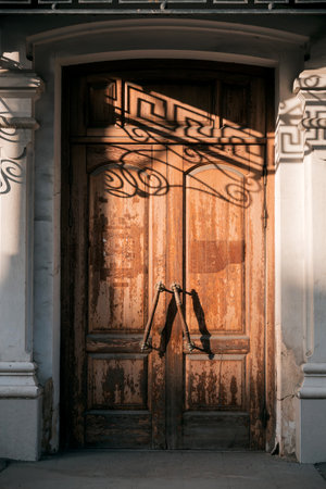 Antique architecture, old vintage closed wooden door with massive handles entrance to the staircase...