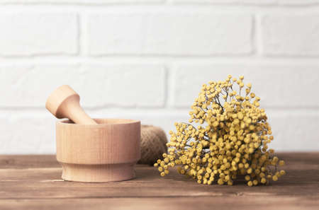 Bouquet of dry tansy tanacetum vulgare in a wooden mortar close-up against a white wall background, medicinal plant, herbal alternative therapy homeopathy, drug recipe.の写真素材