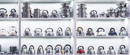 New set of stainless steel pots for cooking, kettles on a shelf in a store, kitchen utensils household goods on a display case.の写真素材