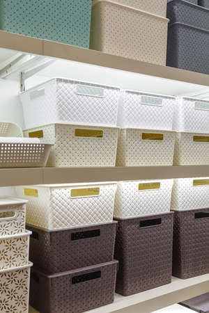 Plastic container boxes on a shelf on a rack for organizing home space and storing things, order and...