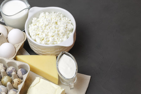 Protein food, farm dairy products on a gray background with copy space. Quail and chicken eggs, milk, cheese, butter, cream, sour cream. Source of calcium, amino acids, vitamin D, vitamin A, B6, B12.の写真素材
