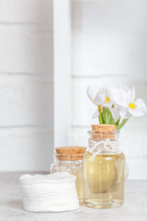 Cosmetology, skin care. Fragrant floral essential massage oil on the background of a white light shelf. The concept of purity.の写真素材