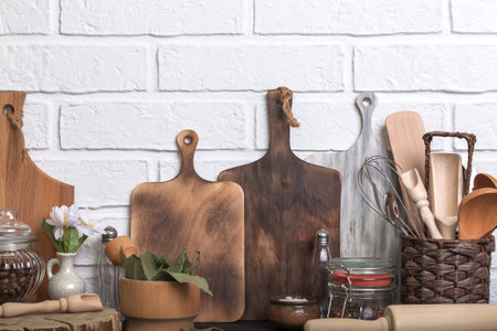 Kitchen utensils and spices on a kitchen countertop against a white brick wall. Food background with...