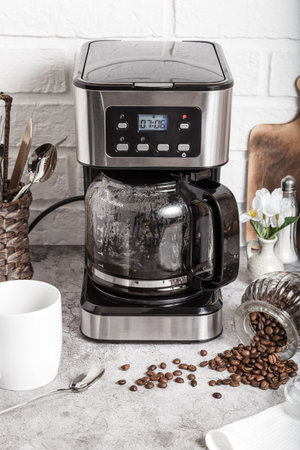 Drip coffee maker and white cup. Preparing hot coffee in a coffee machine. Household appliances on the kitchen table.の写真素材