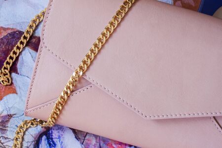 Pink clutch in form of an envelope, decorated with gold chain close-up as background.の写真素材