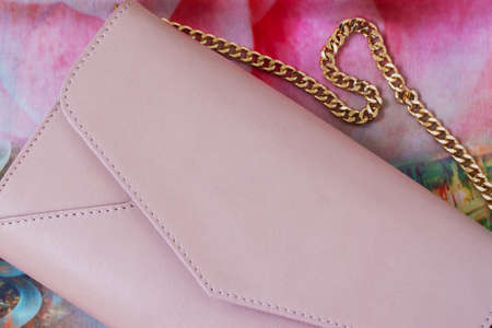 Pink envelope purse , decorated with gold chain close-up as background with space for your logo or text.の写真素材