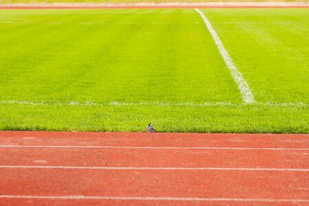 Athletic tracks in stadium for athletes around an football field with natural grass