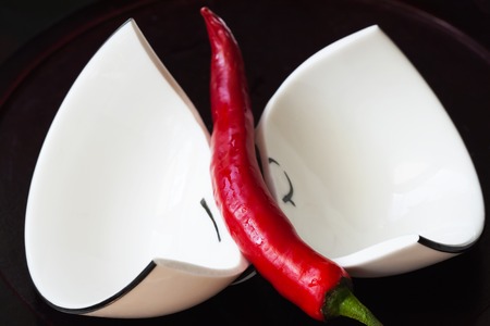 Broken white cup on black background with red pepper paprikaの写真素材