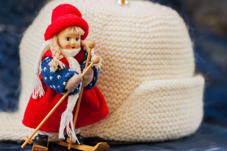 Souvenir little cross country skier on a background of white knitted hat with ear-flaps , for background use. Lots of place for writing text around it.の写真素材