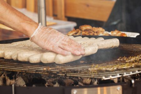 Closeup of man's hands, laid sausages for hot dogs during a summer picnic outdoorsの写真素材