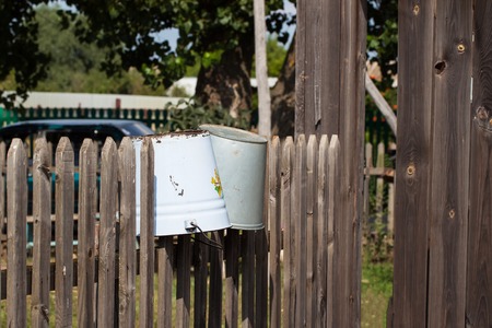 Rural scenery - old rusty rustic buckets hanging on a wicker fenceの写真素材