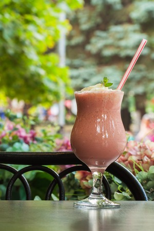 Summer, cafe, terrace, large glass with freshly refreshing frozen berry cocktail, pink, verticalの写真素材