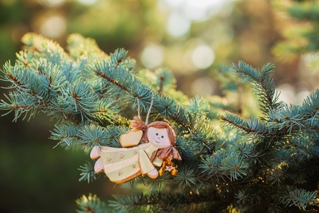 Christmas toy - beautiful wood angel on green spruce and lights on background. Place for text.の写真素材