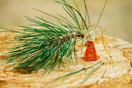 Christmas angel made fromfrom glass with a branch of natural pine on wood background, holiday decorations and backclothsの写真素材