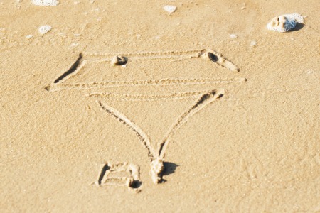 simple drawing in the sand on the beach of sailboat boat, close upの写真素材