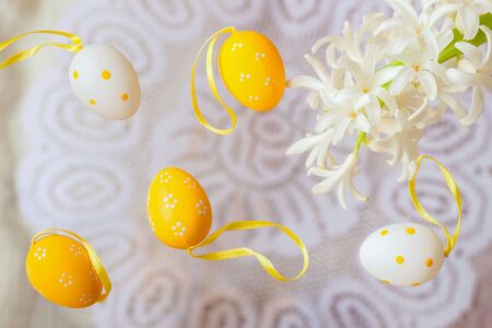 Easter decorative yellow and white painted eggs, natural flowers on a white background of white lace...