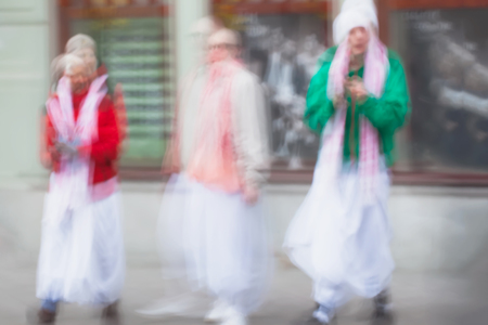Abstract defocused motion blurred Young people group of Hare Krishna movement singing and dancing in...