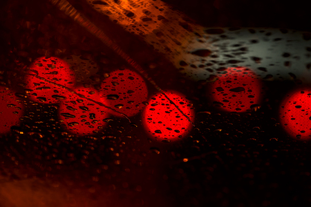 Night lights of urban traffic seen through the windshield in rainy weather. Abstract background of urban city in night with light bokeh . Concept of night city life and carsの写真素材
