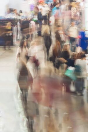 Abstract people walking in exhibition hall, trade fair show, defocused motion blurred backgroundの写真素材