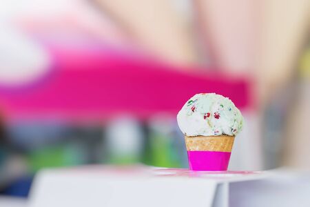 Vanilla ice cream in waffle cone topped with colorful sprinkles, bright blurry background. Selective focus. Copy space. Concept of love, sweets, lifestyleの写真素材