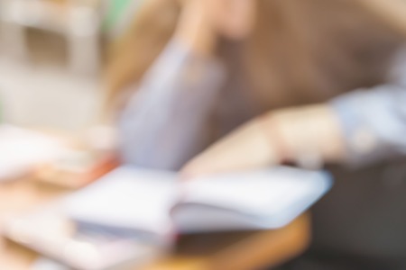 Close-up of Book in hands of young girl in book store or in library, which attentively reading book, abstract blurred image. Concept of education, manuals, textbooks, school, studyの写真素材