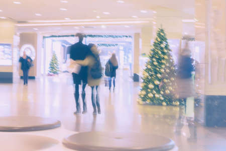 Abstract defocused motion blurred unrecognizable young people walking in the shopping center, on the pre-Christmas holidays, urban lifestyle concept, backgroundの写真素材