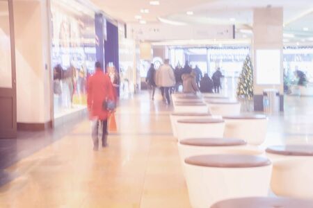 Abstract defocused motion blurred unrecognizable people people of different ages in the shopping center hurrying for gifts for loved ones in the pre-Christmas holidaysの写真素材