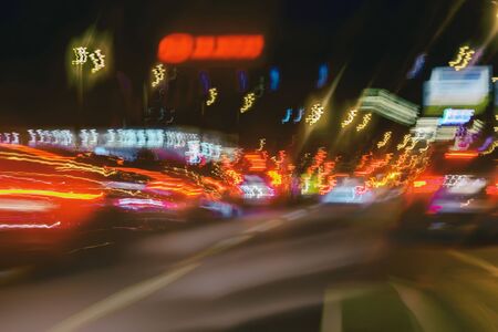 Abstract blurred colorful background of urban street night traffic with bokeh lights. Auto, city street lights, speed. Selective focus.の写真素材