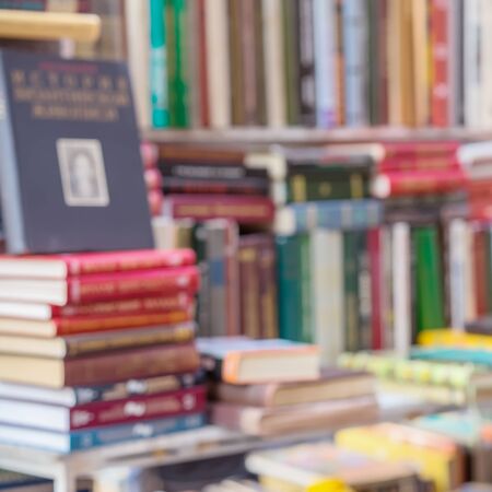 Many books, textbooks, fiction in rows lying on table, on shelves in library, in modern urban...
