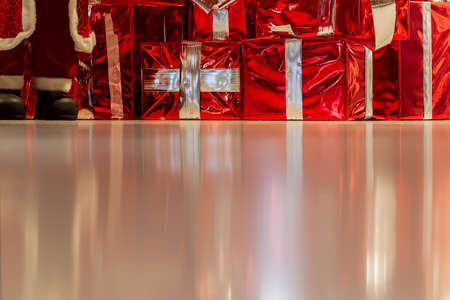 Many gift boxes with golden ribbons and Santas feet on shiny background. Christmas background, gifts, shoping concept. Copy spaceの写真素材